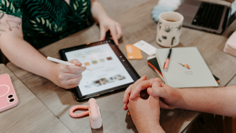 Two people in a business meeting discussing a branding kit displayed on an ipad